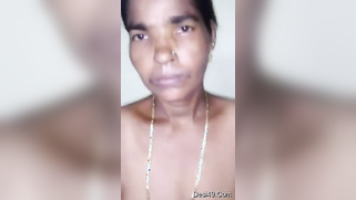 Indian aunty with saggy body stands against the wall posing on camera